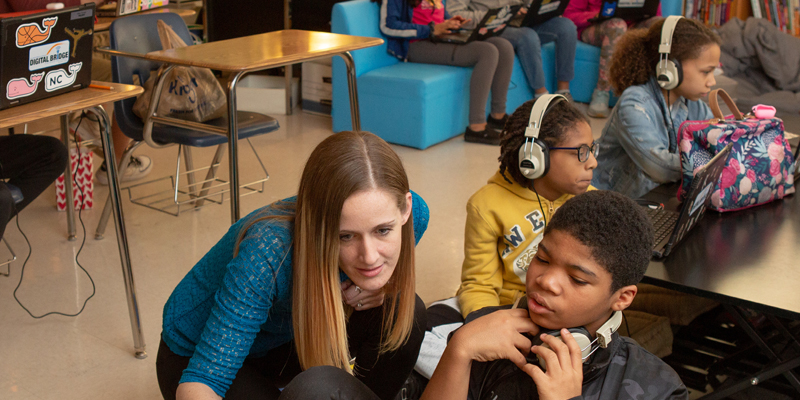 A teacher demonstrating a visual aid with a student in a library