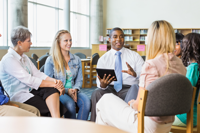 African-American male teacher leading discussion group of adults and teens