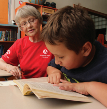 Image of an Americorps teacher with a Pre-K student reading a book