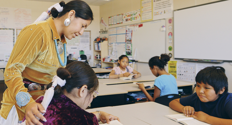 Indigenous Navajo teacher and students in an elementary school classroom.