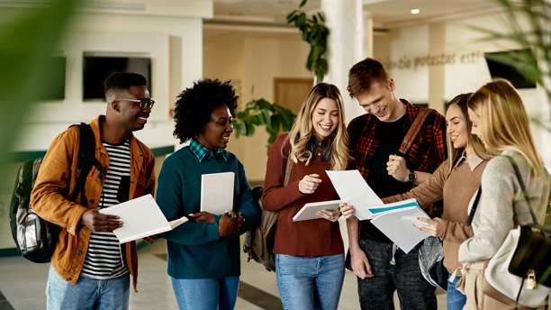 Image of happy female student showing test results to her friends while standing in a lobby